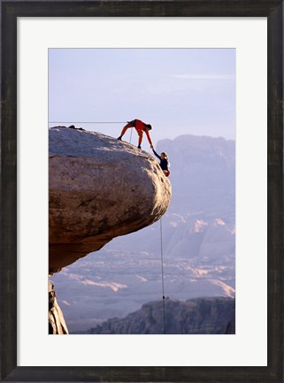 Framed Side profile of a young man pulling a young woman onto a rock Print