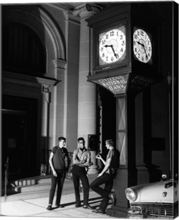 Framed Young men standing below clock at night Print