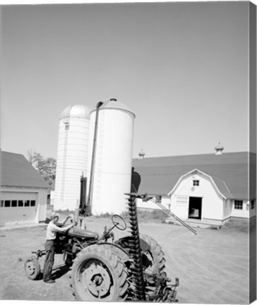 Framed USA, Farmer Working on Tractor, Agricultural Buildings in the Background Print