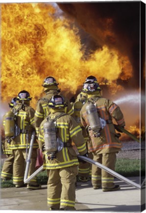 Framed Rear view of a group of firefighters extinguishing a fire vertical Print