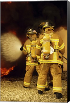 Framed Rear view of three firefighters extinguishing a fire Print