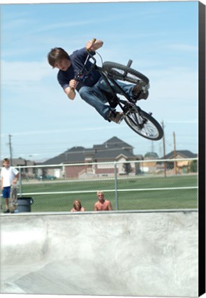 Framed Low angle view of a teenage boy performing a stunt on a bicycle over ramp Print