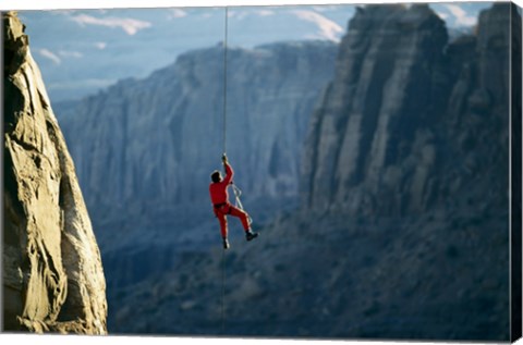 Framed Rear view of a man rappelling down a rock Print