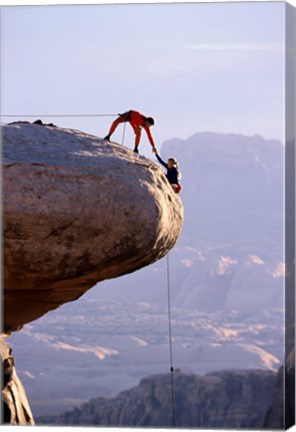 Framed Side profile of a young man pulling a young woman onto a rock Print