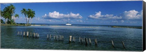 Framed Wooden posts in the sea with a boat in background, Laughing Bird Caye, Victoria Channel, Belize Print