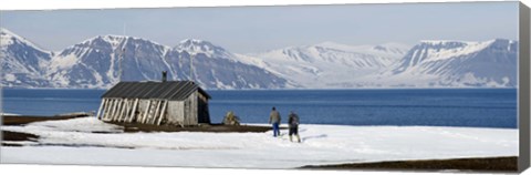 Framed Two hikers standing on the beach near a hunting cabin, Bellsund, Spitsbergen, Svalbard Islands, Norway Print