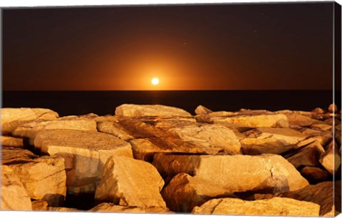 Framed moon rising behind rocks lit by a nearby fire in Miramar, Argentina Print