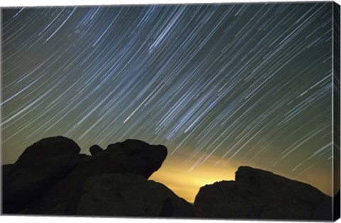 Framed Light pollution illuminates the sky and star tails above large boulders Print