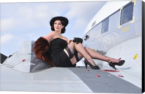 Framed Glamorous woman in 1940&#39;s style attire sitting on a vintage aircraft Print