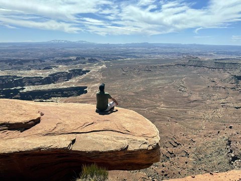 Framed Adult Male Sitting on the Edge Of a Stunning Viewpoint Print