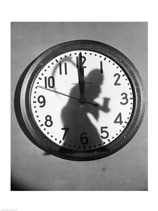 Framed Close-up of the shadow of a person carrying a scythe on a clock Print