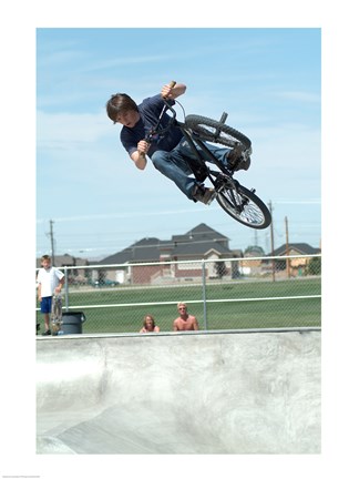 Framed Low angle view of a teenage boy performing a stunt on a bicycle over ramp Print