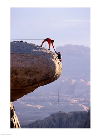 Framed Side profile of a young man pulling a young woman onto a rock Print