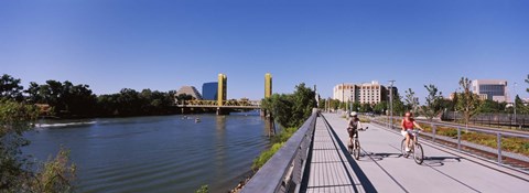 Framed Bicyclists along the Sacramento River with Tower Bridge in background, Sacramento, Sacramento County, California, USA Print