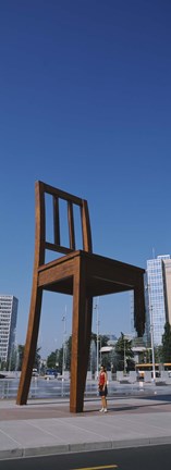 Framed Woman standing under a sculpture of large broken chair, Geneva, Switzerland Print