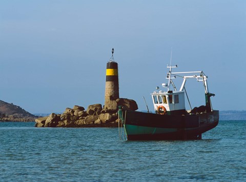 Framed Fishing trawler in front of a lighthouse at Port Saint-Sauveur, Ile Grande, Cotes-d&#39;Armor, Brittany, France Print