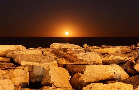 Framed moon rising behind rocks lit by a nearby fire in Miramar, Argentina Print