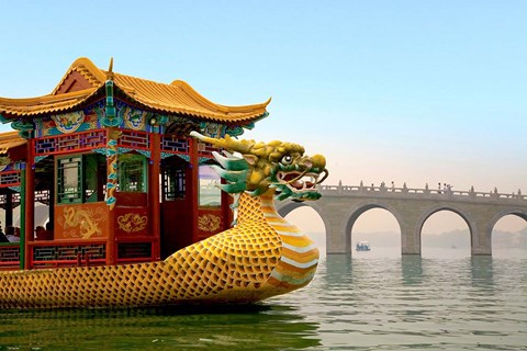 Framed Summer Palace, a traditional Dragon Boat passes the Seventeen Arch Bridge, Kunming lake, Beijing, China Print