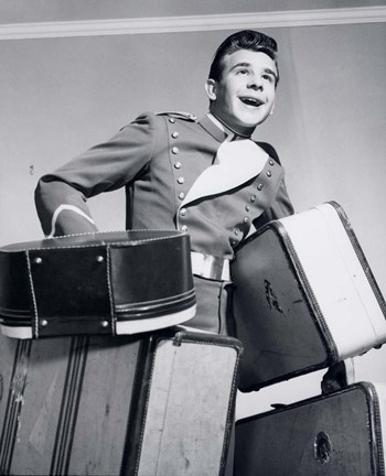 Framed 1950s Smiling Bellboy Carrying Four Bags Of Luggage Print