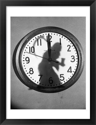 Framed Close-up of the shadow of a person carrying a scythe on a clock Print