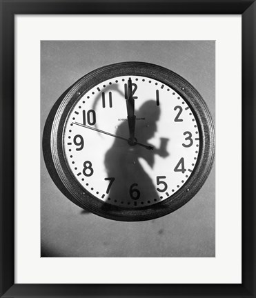 Framed Close-up of the shadow of a person carrying a scythe on a clock Print