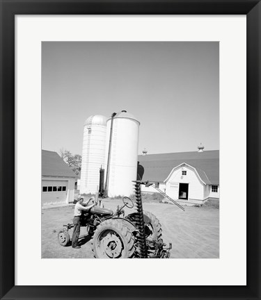 Framed USA, Farmer Working on Tractor, Agricultural Buildings in the Background Print