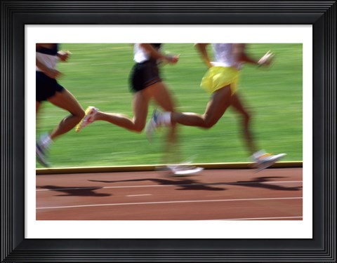 Framed Low section view of male athletes running on a running track Print