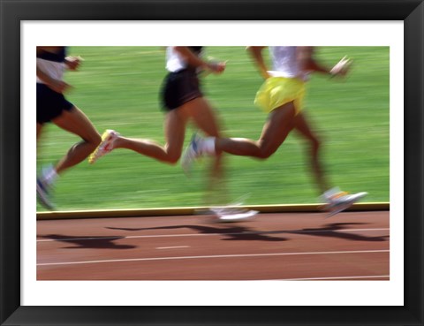 Framed Low section view of male athletes running on a running track Print