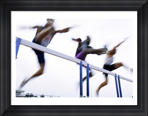 Framed Low angle view of three men jumping over a hurdle Print
