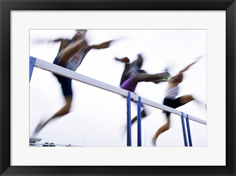 Framed Low angle view of three men jumping over a hurdle Print