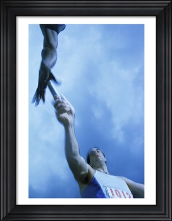 Framed Low angle view of runners passing a baton in a relay race Print