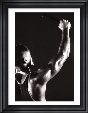 Framed Male runner holding up a relay baton Print