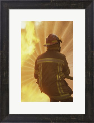Framed Rear view of a firefighter extinguishing a fire Print