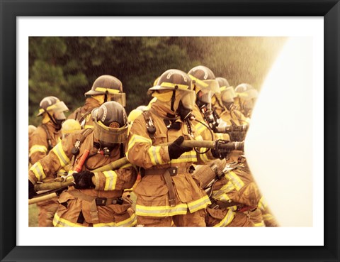 Framed Group of firefighters spraying water with a fire hose Print