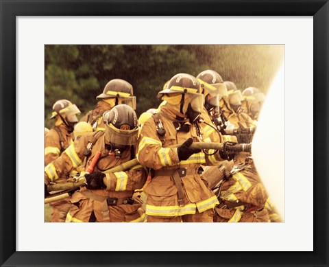 Framed Group of firefighters spraying water with a fire hose Print