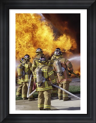 Framed Rear view of a group of firefighters extinguishing a fire vertical Print
