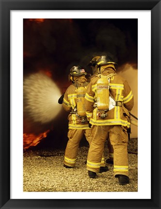 Framed Rear view of three firefighters extinguishing a fire Print