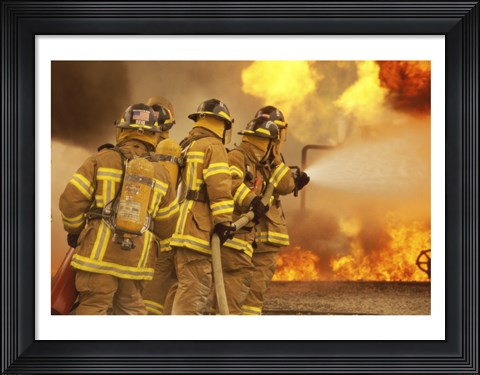 Framed Rear view of a group of firefighters extinguishing a fire and flames Print