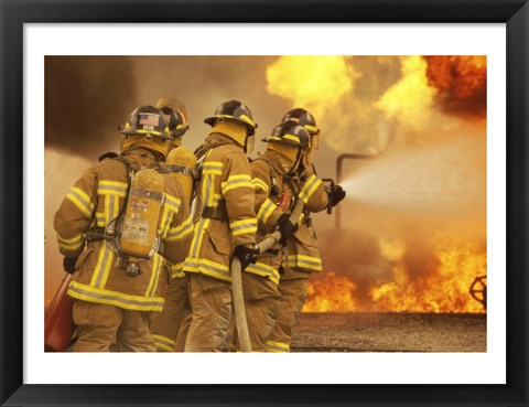 Framed Rear view of a group of firefighters extinguishing a fire and flames Print