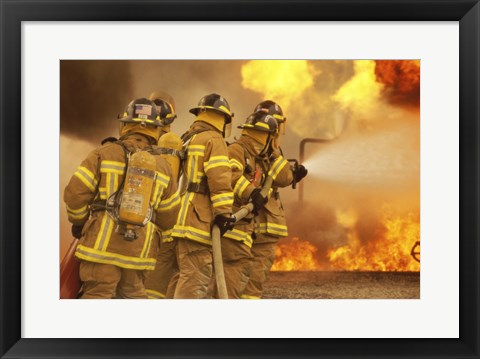 Framed Rear view of a group of firefighters extinguishing a fire and flames Print