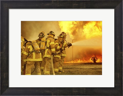 Framed Rear view of a group of firefighters extinguishing a fire Print