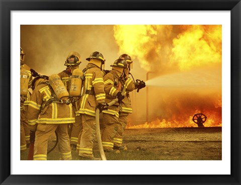 Framed Rear view of a group of firefighters extinguishing a fire Print