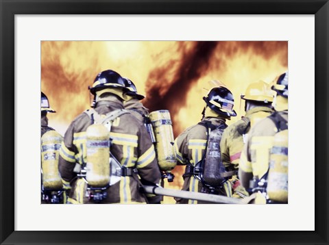 Framed Rear view of a group of firefighters holding water hoses Print