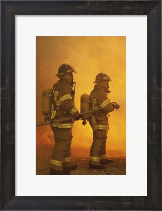 Framed Rear view of two firefighters extinguishing a fire Print