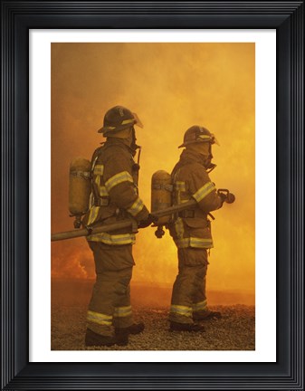 Framed Rear view of two firefighters extinguishing a fire Print