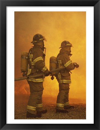 Framed Rear view of two firefighters extinguishing a fire Print