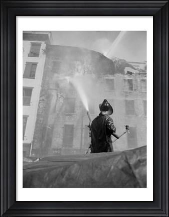 Framed Firefighter pouring water on burning building, low angle view Print