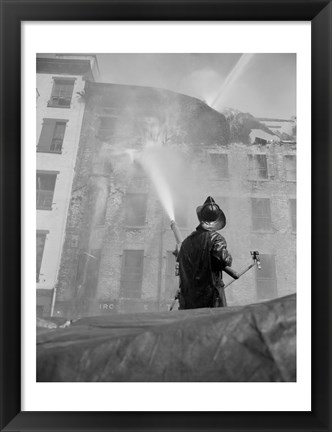 Framed Firefighter pouring water on burning building, low angle view Print