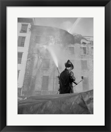 Framed Firefighter pouring water on burning building, low angle view Print