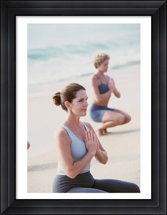 Framed Young woman and a mid adult woman meditating on the beach Print